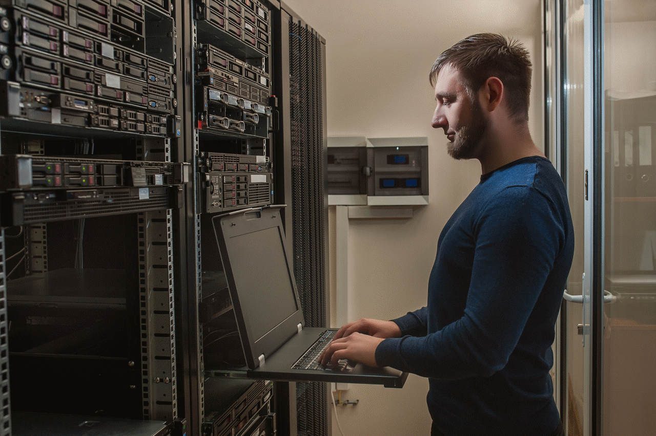 Man typing on a rack-mounted console in a server room