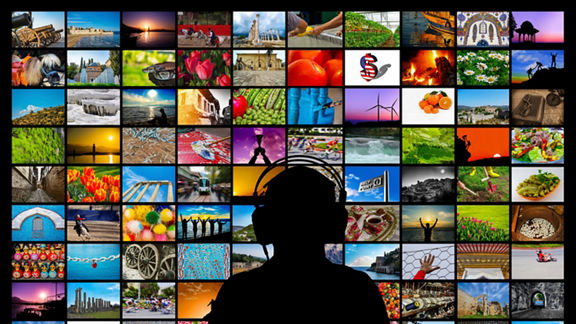 Silhouette of man sitting in front of video wall watching multimedia screens