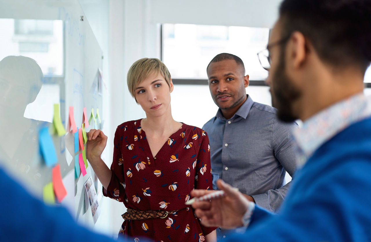 Image of employees having a discussion at a whiteboard