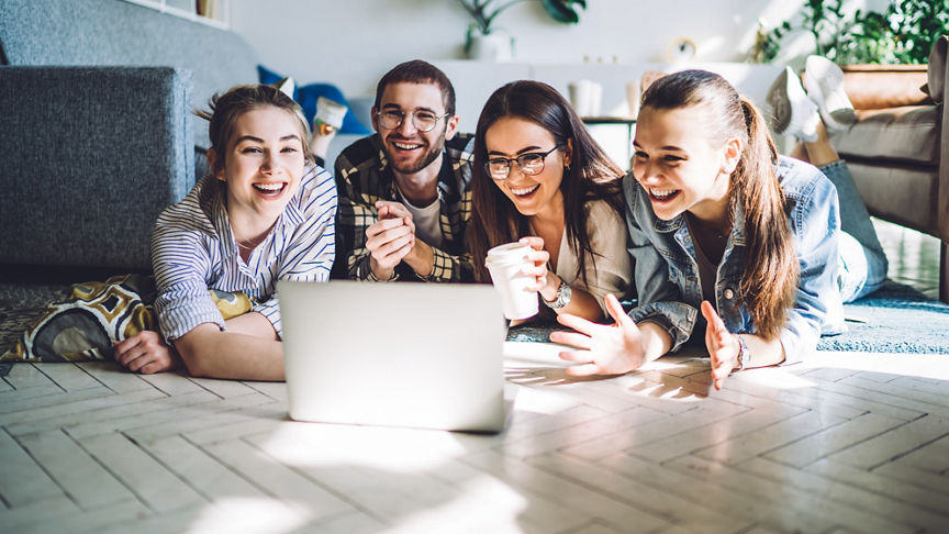 Happy teens having fun looking at laptop on floor of family room