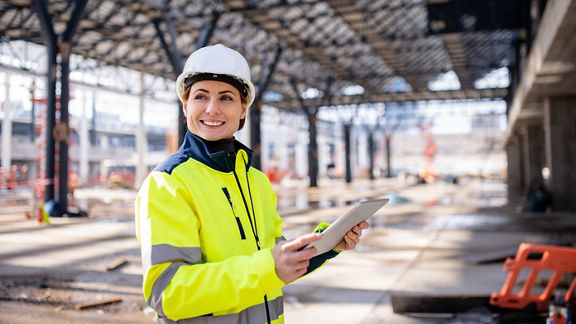 A woman engineer with a tablet standing on a construction site, working.