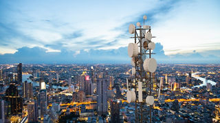 A radio tower rises above a modern cityscape