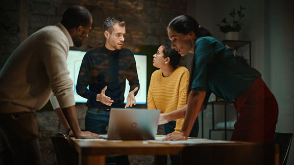 A diverse team has a conversation in a meeting room.