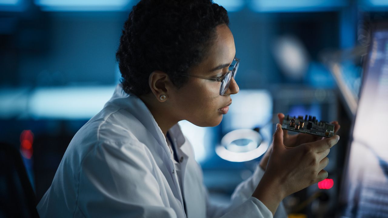 Technician in white coat holds a module