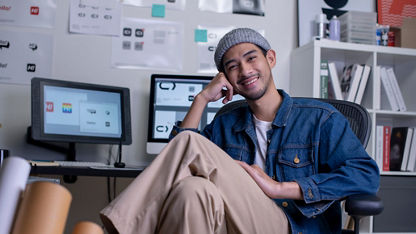 A graphic designer sitting and smiling at the camera