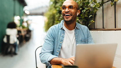 A happy man working on his laptop outside.