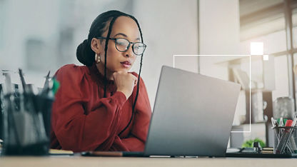最新のオフィスでデスクに座り、開いたノートブック PC で情報を確認するビジネス・プロフェッショナル