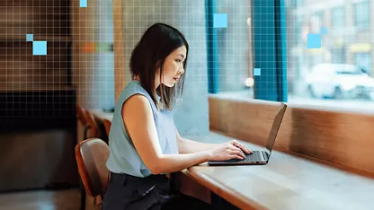 高いカウンターの前に座り、開いたノートブック PC のキーボードを打っているビジネス・プロフェッショナル