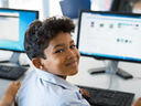 Student smiling at camera while using a computer