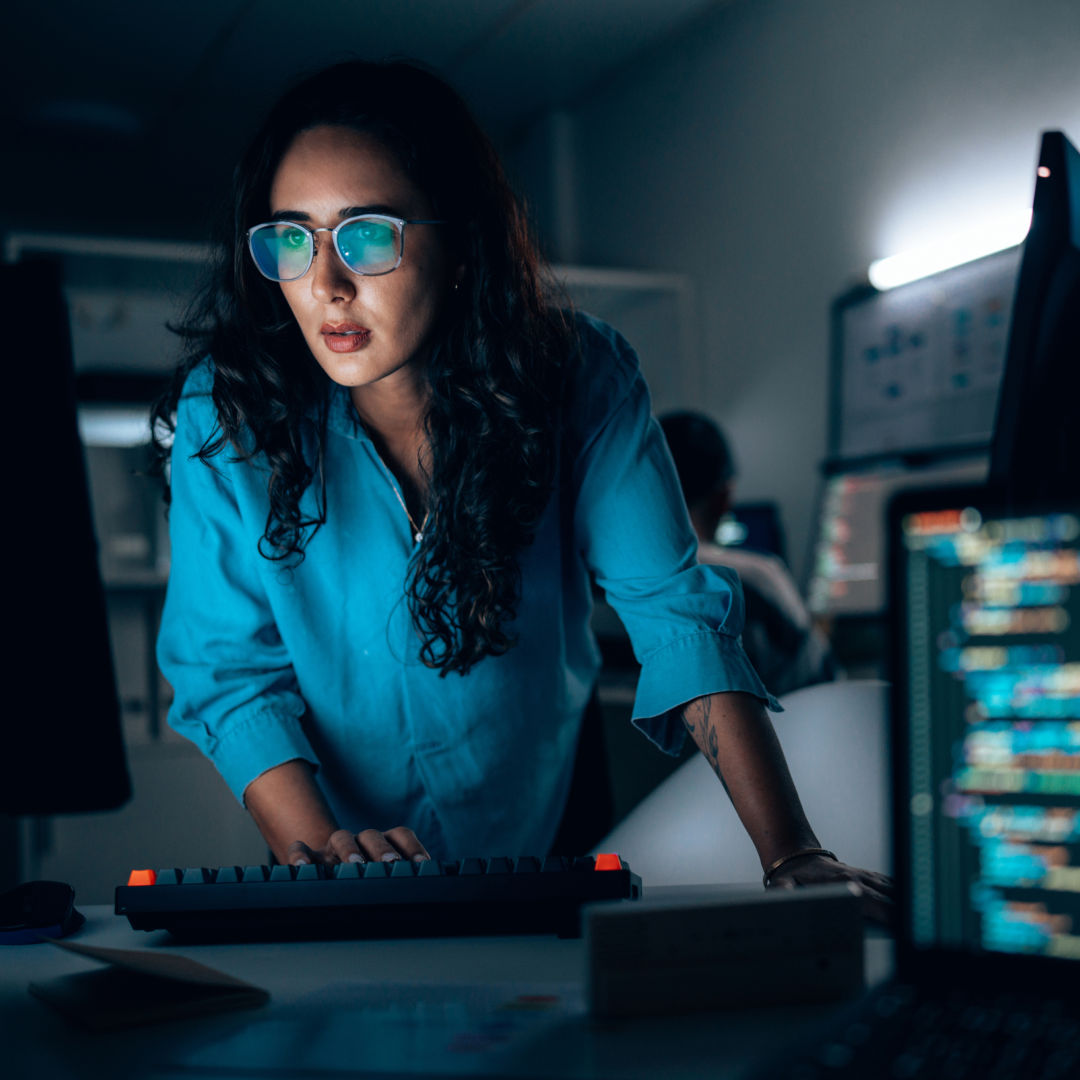 Person typing and looking at a monitor at a workstation.