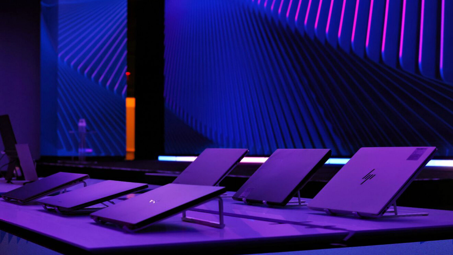 Laptops displayed on tables under purple lighting at the Intel CES 2026 Technology Showcase.