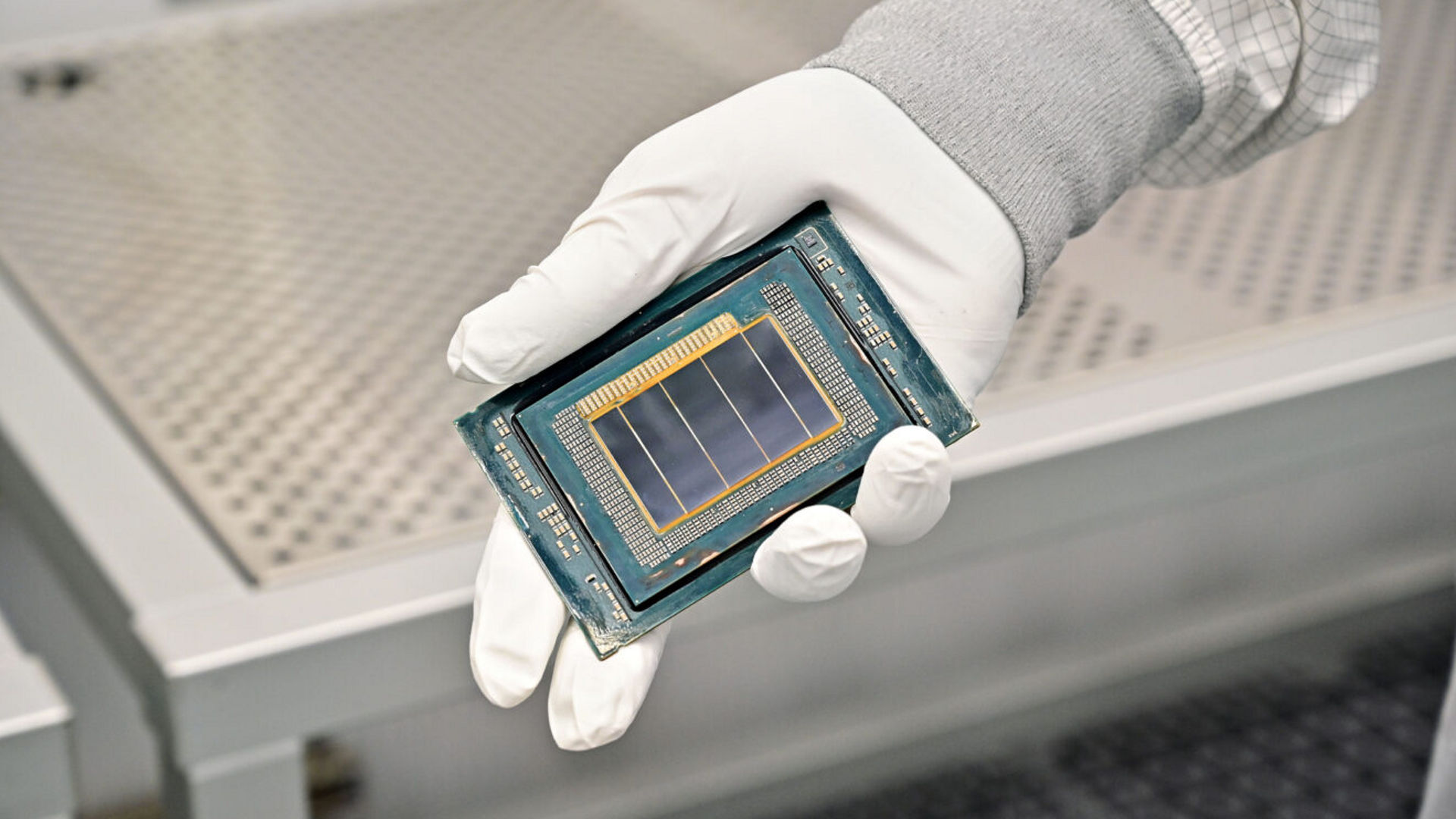 A technician in a cleanroom glove holds an Intel Clearwater Forest processor chip.