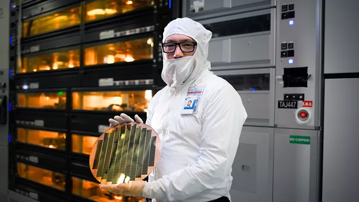 An Intel factory employee holds a wafer with 3D stacked Foveros technology at an Intel fab in Hillsboro, Oregon.