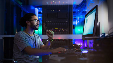 Man in data center operations room remotely managing server