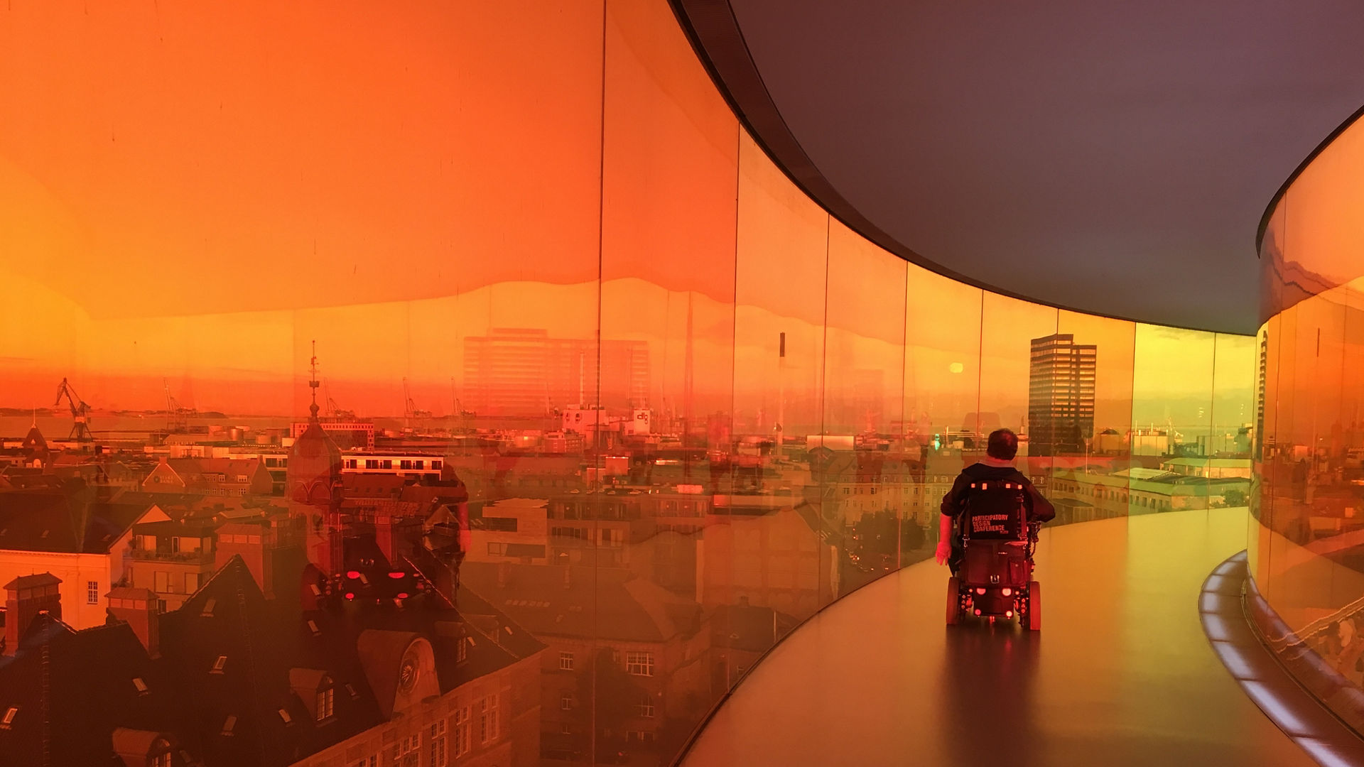 Image of a person in a wheelchair on an elevated hallway with windows