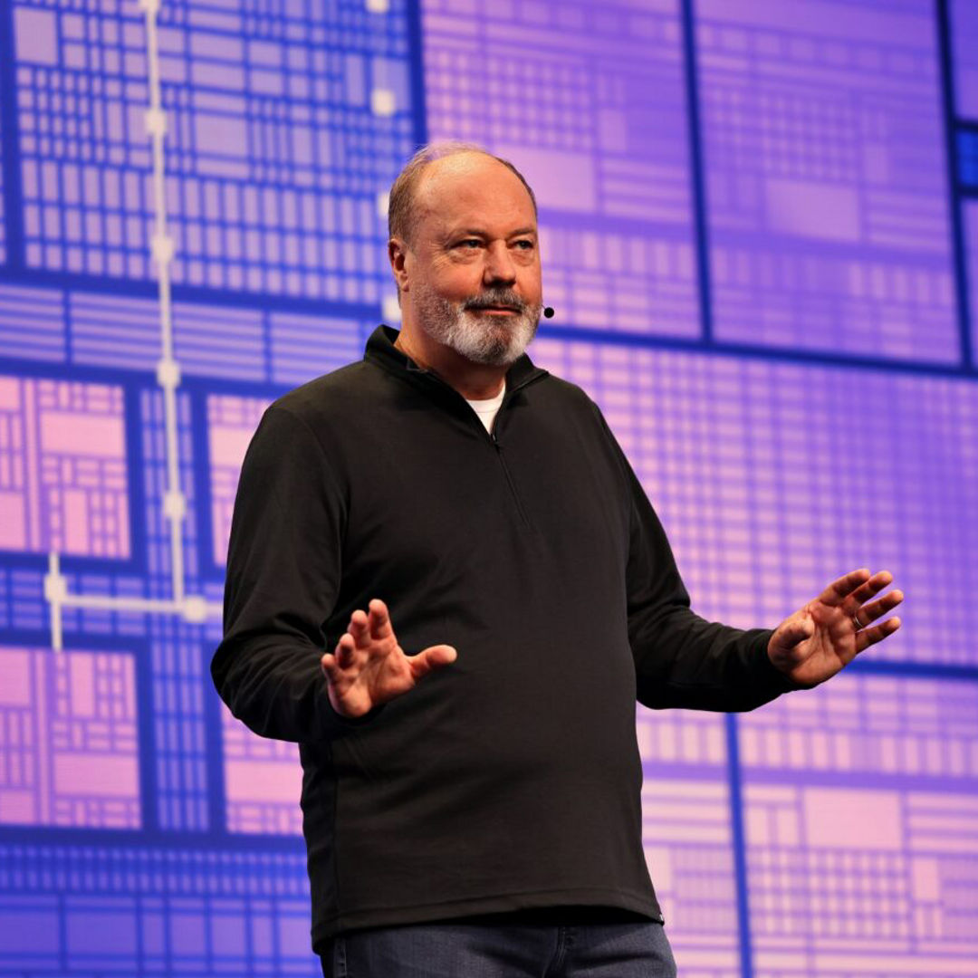 Presenter speaking on a purple-lit CES stage.