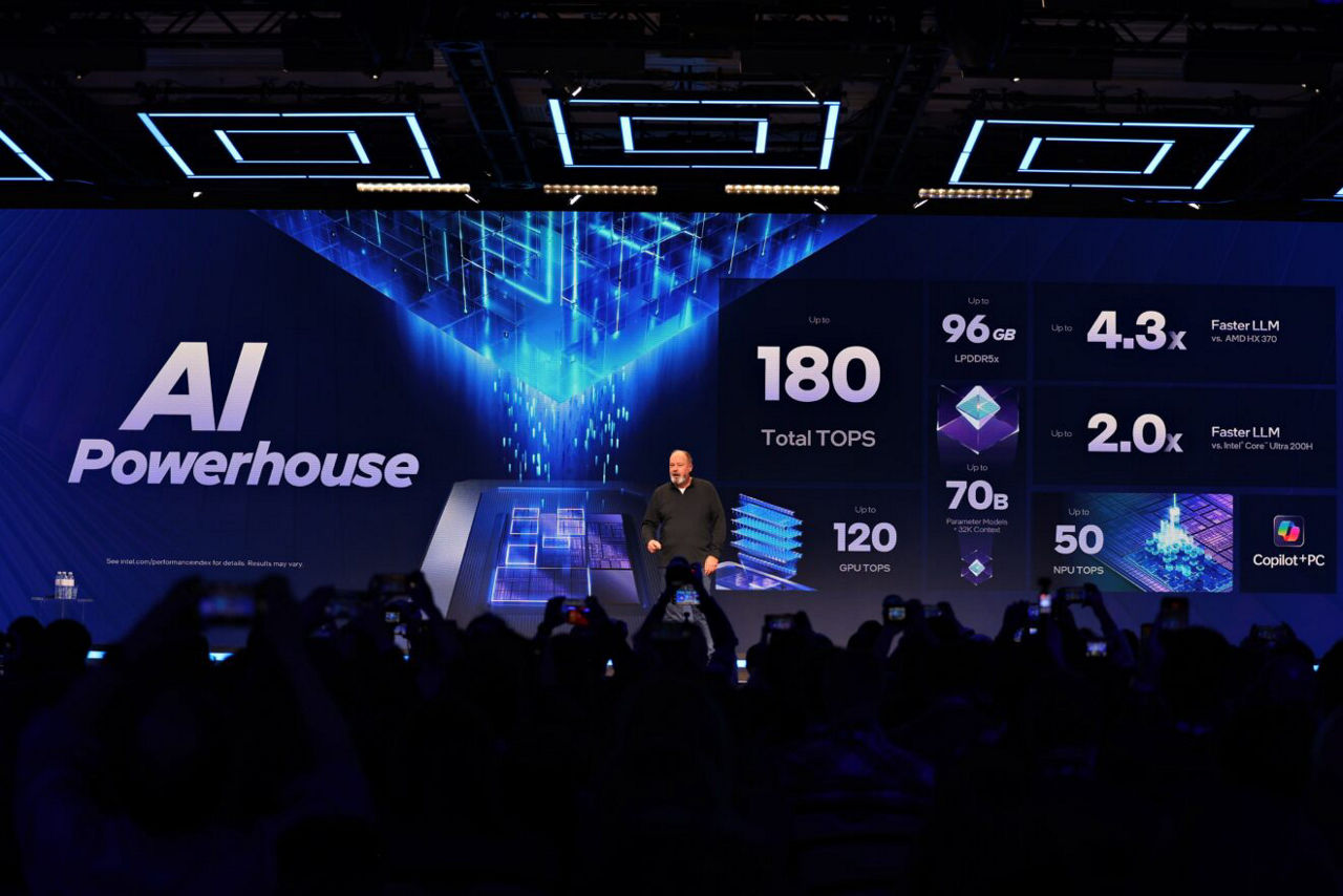 Presenter onstage with an Intel AI performance presentation.