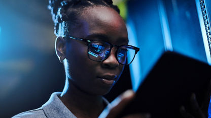 A close-up view of a person’s face as they look at a hand-held tablet