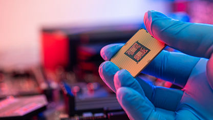 Gloved hand holding a chip with red backlighting.