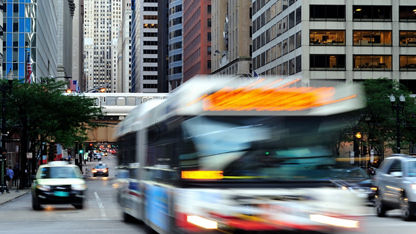 A Chicago public transportation bus drives on a traffic-heavy street in downtown Chicago