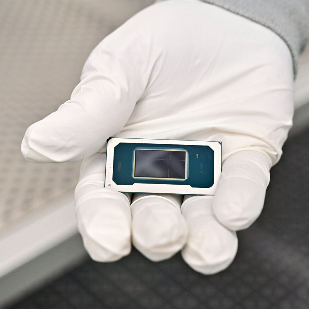 An Intel manufacturing technician holds a Panther Lake chip inside the cleanroom of Intel’s new Fab 52 in Chandler, Arizona, in September 2025. Fab 52 is the U.S. home to Intel 18A, where Panther Lake, a consumer and client laptop processor, is being manufactured.