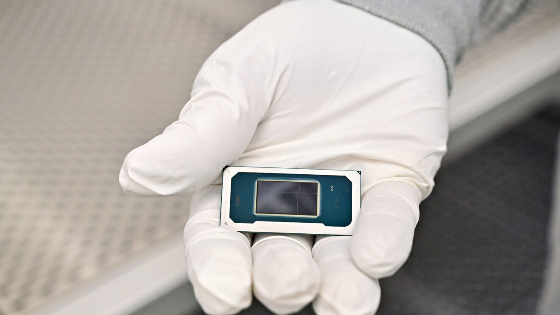 An Intel manufacturing technician holds a Panther Lake chip inside the cleanroom of Intel’s new Fab 52 in Chandler, Arizona, in September 2025. Fab 52 is the U.S. home to Intel 18A, where Panther Lake, a consumer and client laptop processor, is being manufactured.