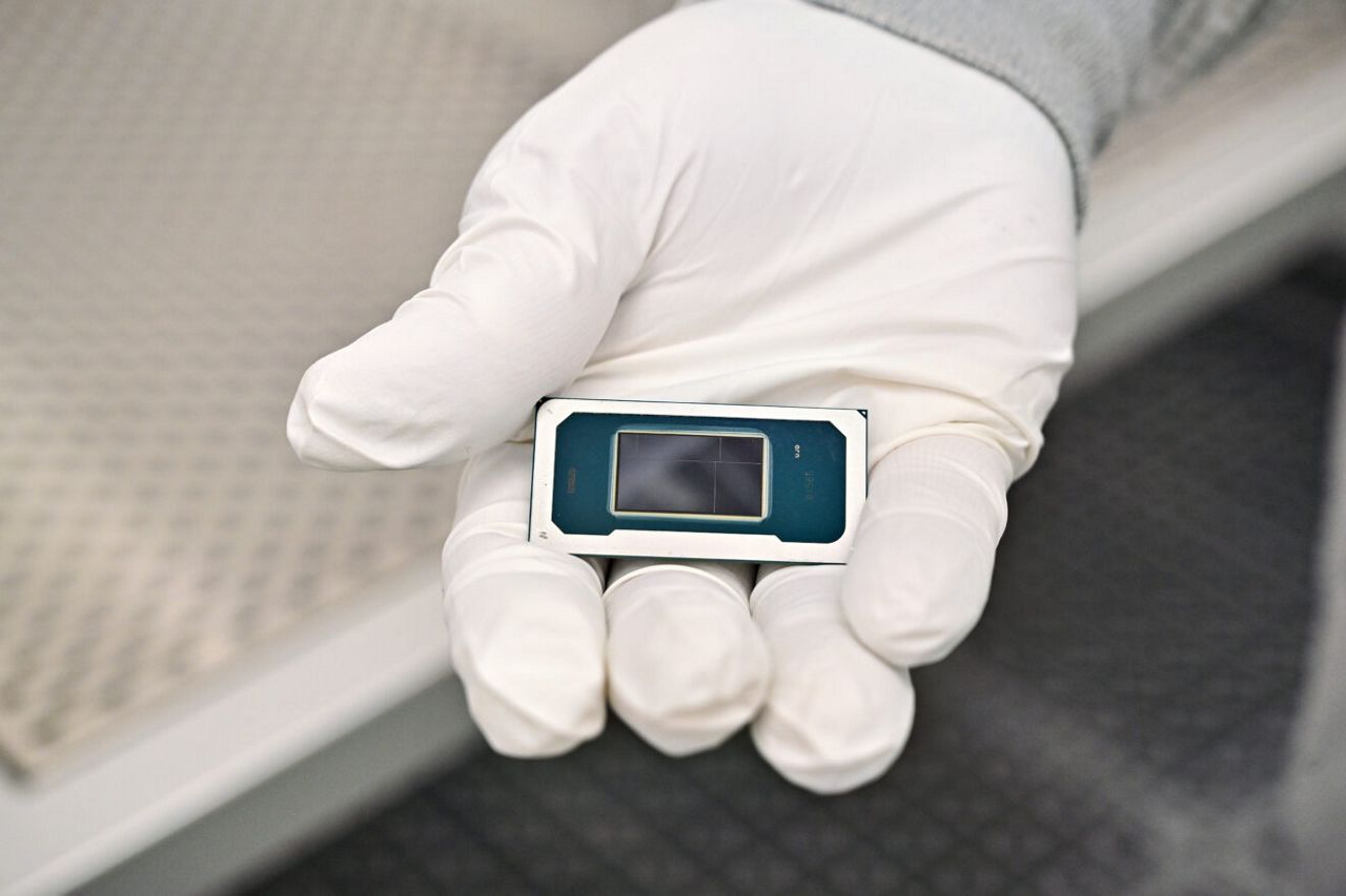 An Intel manufacturing technician holds a Panther Lake chip inside the cleanroom of Intel’s new Fab 52 in Chandler, Arizona, in September 2025. Fab 52 is the U.S. home to Intel 18A, where Panther Lake, a consumer and client laptop processor, is being manufactured.