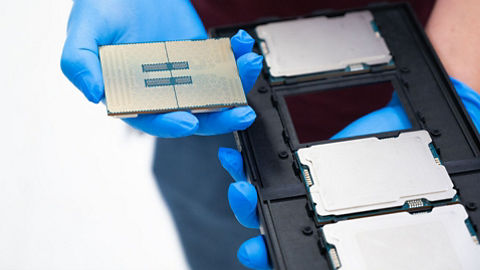 Person wearing a blue glove holding a chip directly from the cassette (Intel Corporation)