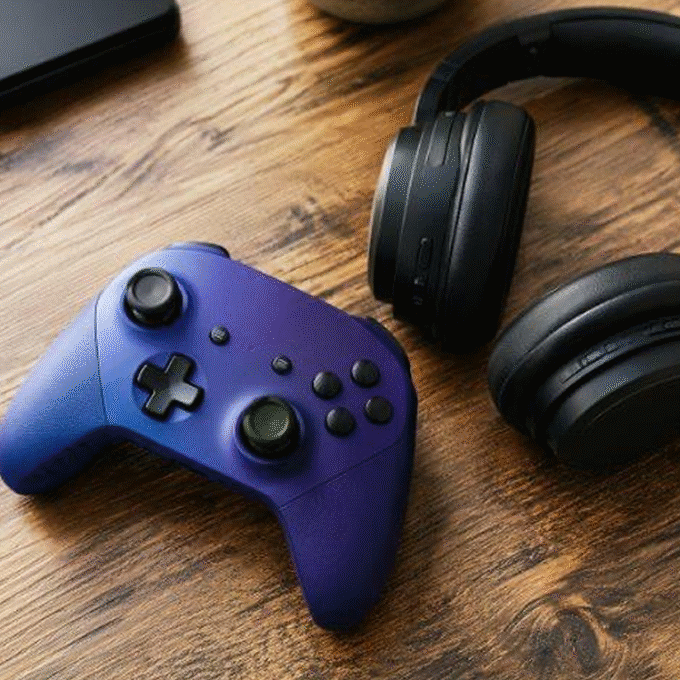 Imagem de estilo de vida com um controle para jogos e um fone de ouvido supra-auricular em uma superfície de desktop. Destinado ao uso em conteúdo de jogos, entretenimento e experiência de jogos para dispositivos portáteis.