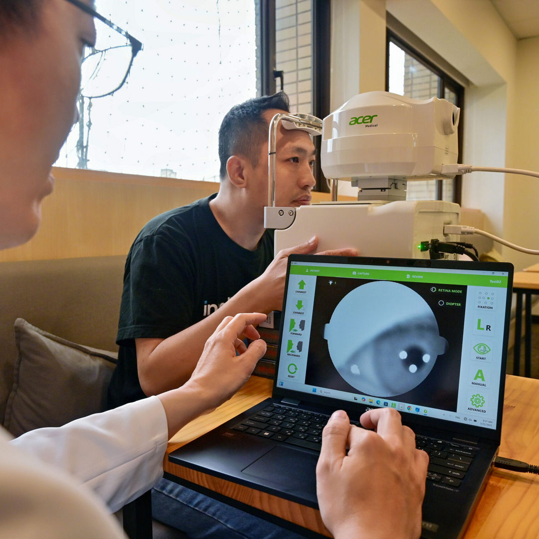 Dr. Hsieh Yi-Ting reviews a patient's eye scan on a laptop connected to a fundus camera.