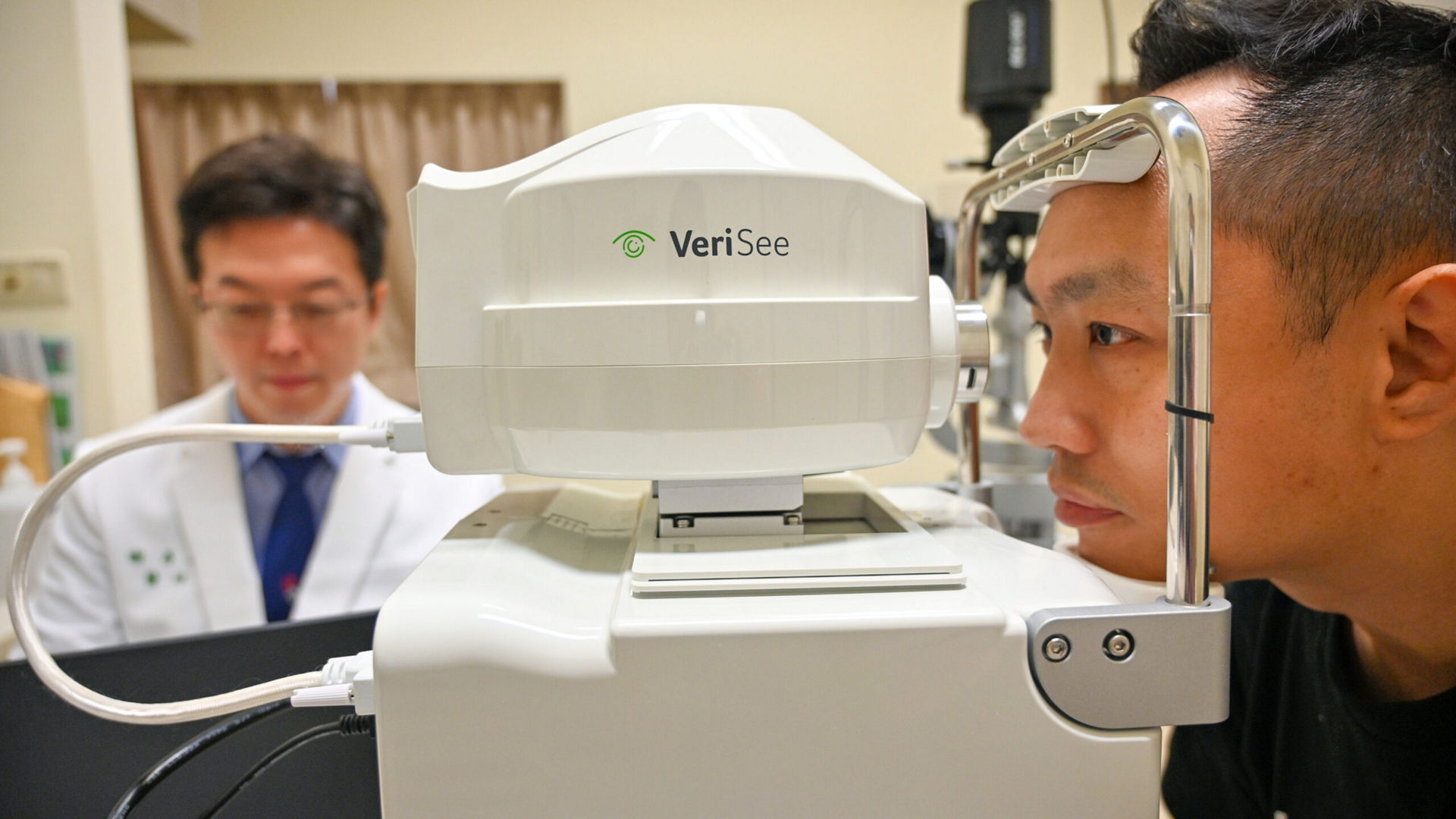 Dr. Hsieh Yi-Ting (left) demonstrates detailed eye scans of a patient on his Acer Travelmate Spin P4 AI PC, connected to a high-resolution non-mydriatic fundus camera. Thanks to AI algorithms developed using Intel OpenVINO tool kits, he sees results in just 10 seconds. (Credit: Intel Corporation)