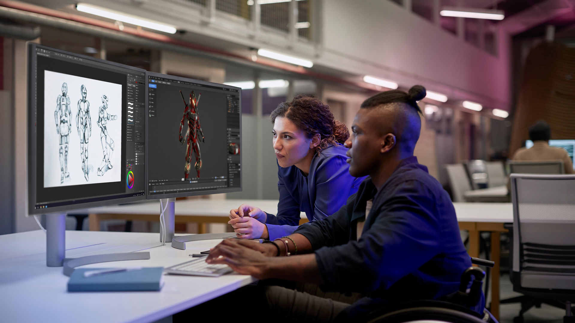 Two individuals looking at dual monitors in an office setting