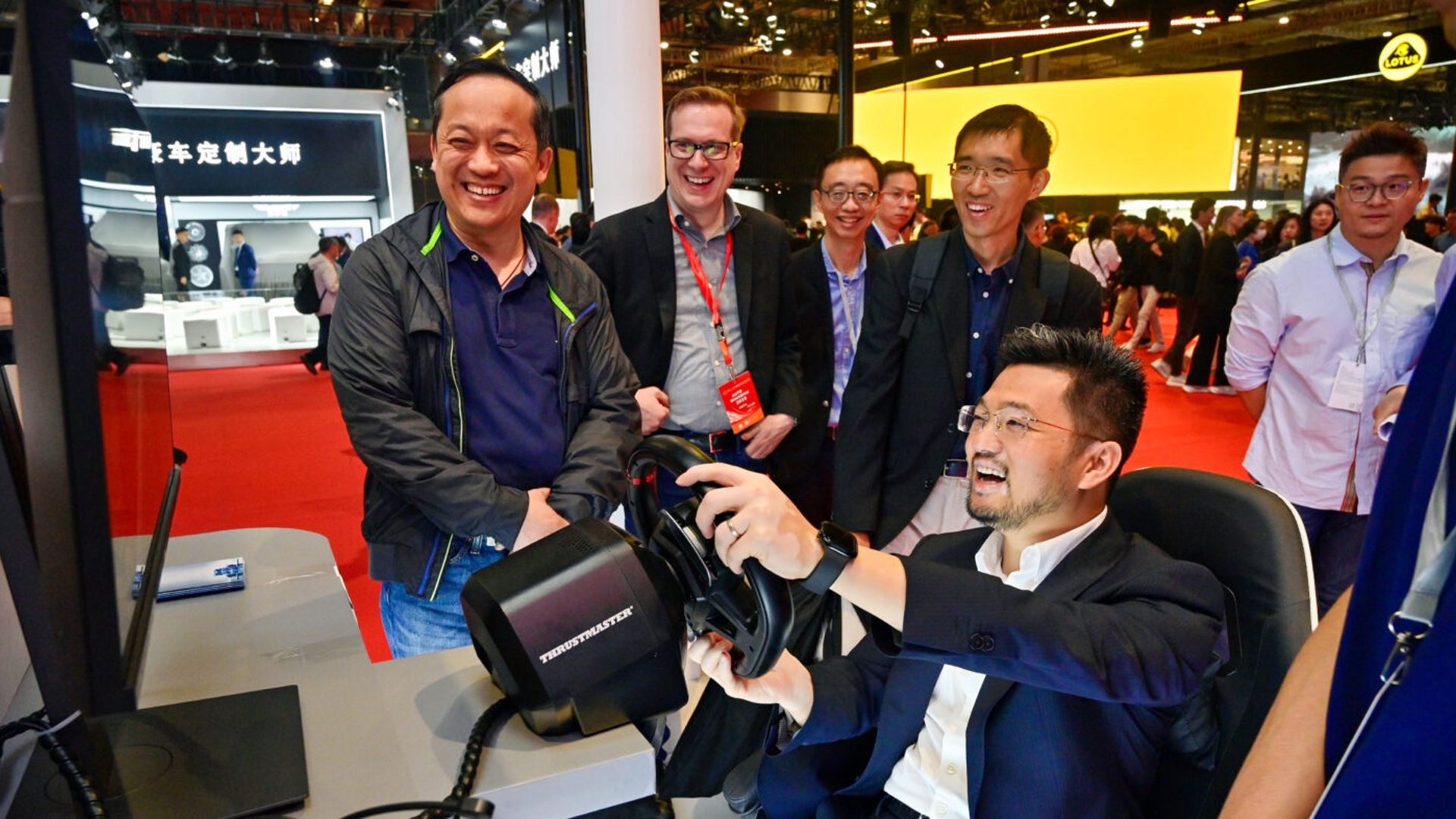 Yu Peng of XPeng uses a driving simulator while others watch at Auto Shanghai 2025.