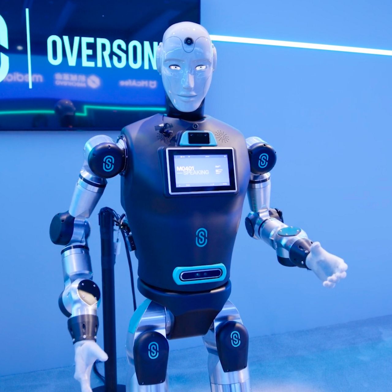 Image of a humanoid robot with a screen on its chest in a confrence room setting