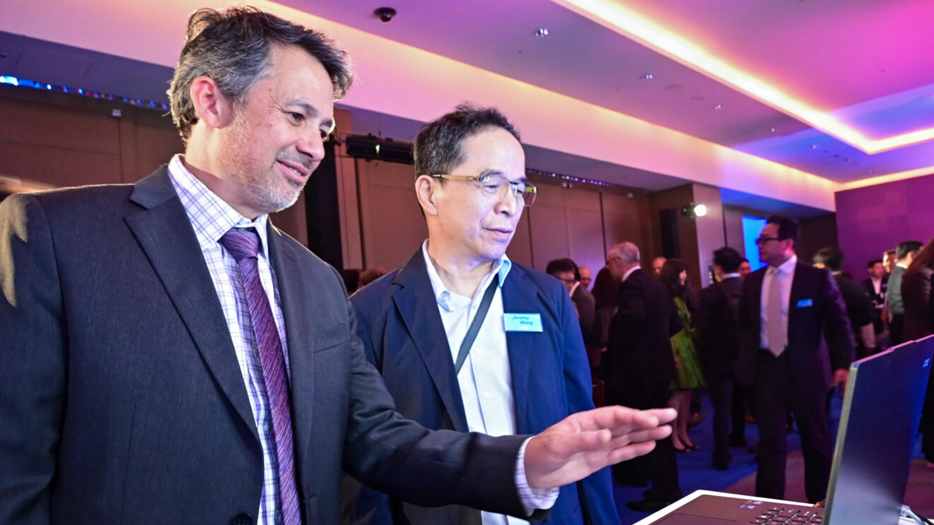 Two men look at a laptop screen during a technology demonstration at Computex 2025.