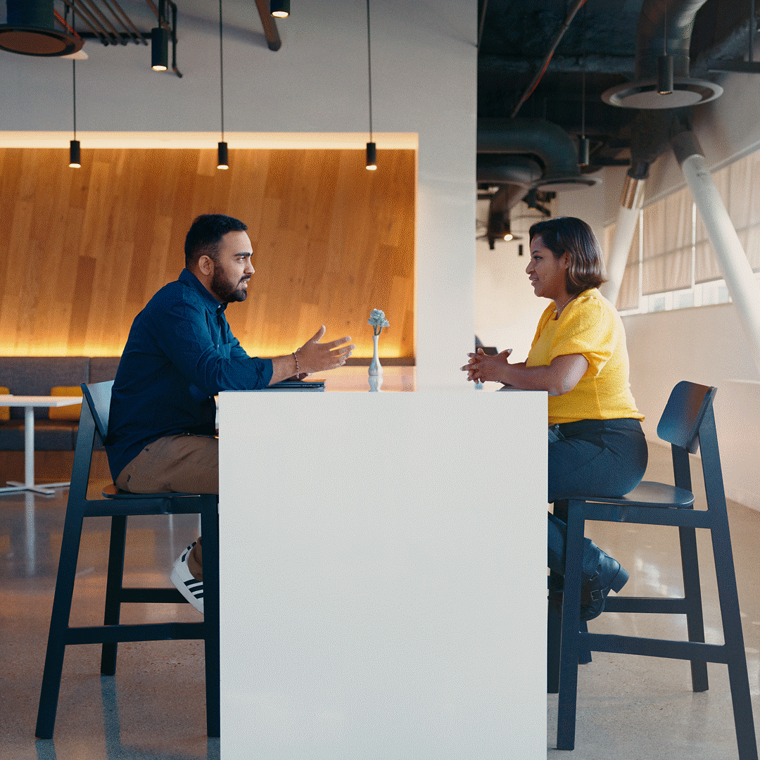 Two Intel employees in office sitting on stools at a tall table