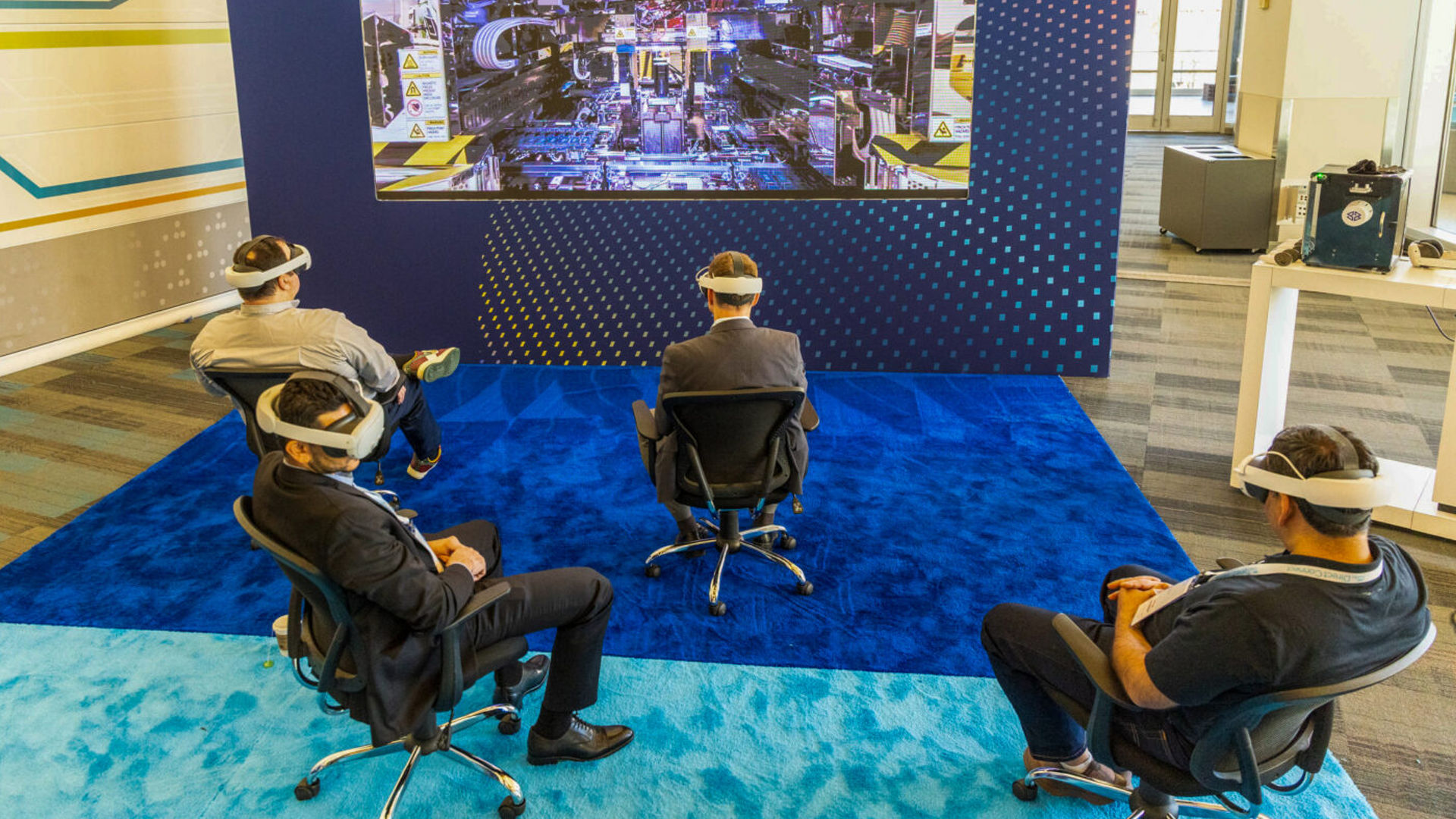 Attendees wearing VR headsets sit in front of a large screen at Intel Foundry Direct Connect.