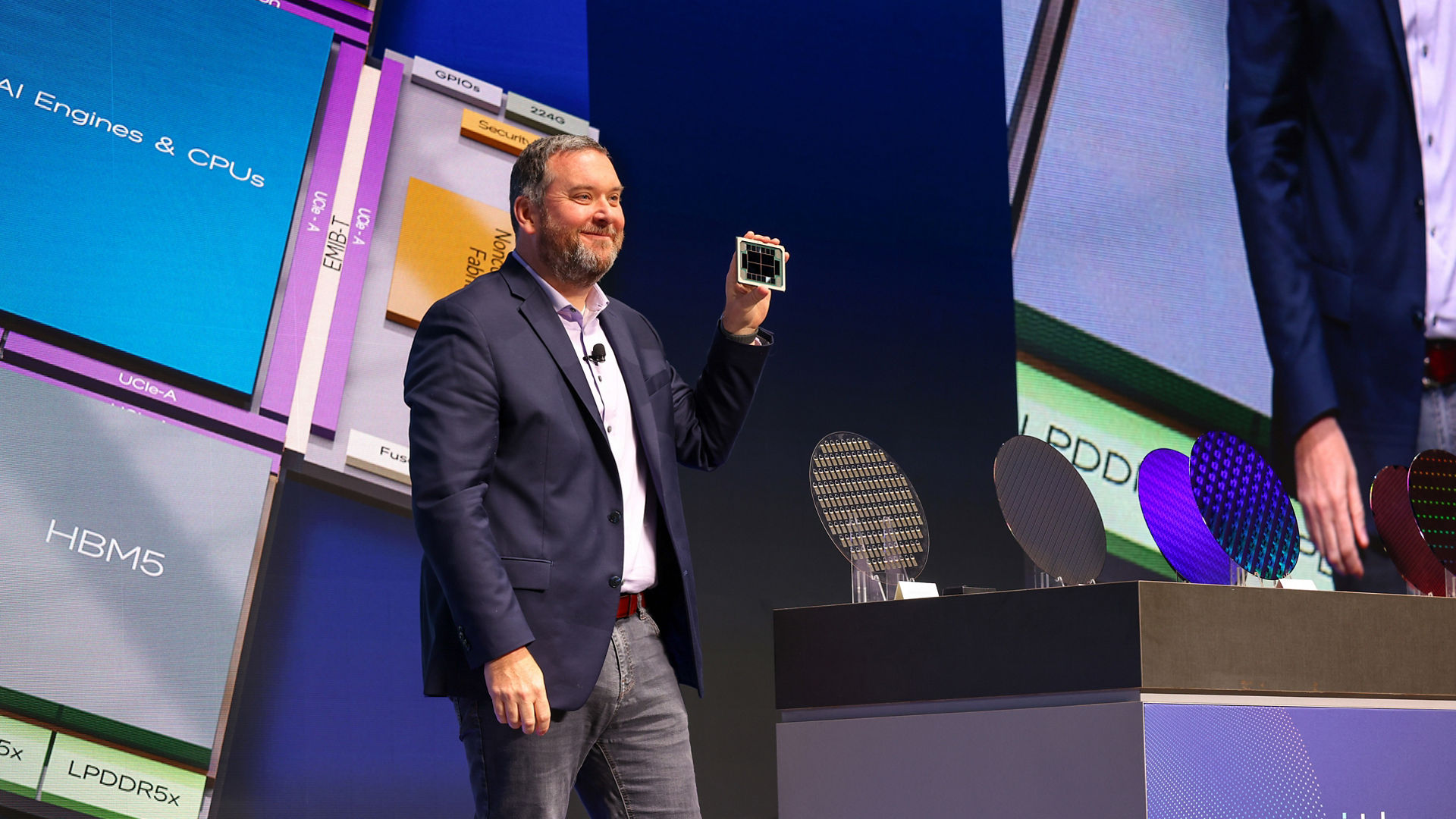 Kevin O’Buckley, general manager of Foundry Services, displays a semiconductor wafer during a keynote.