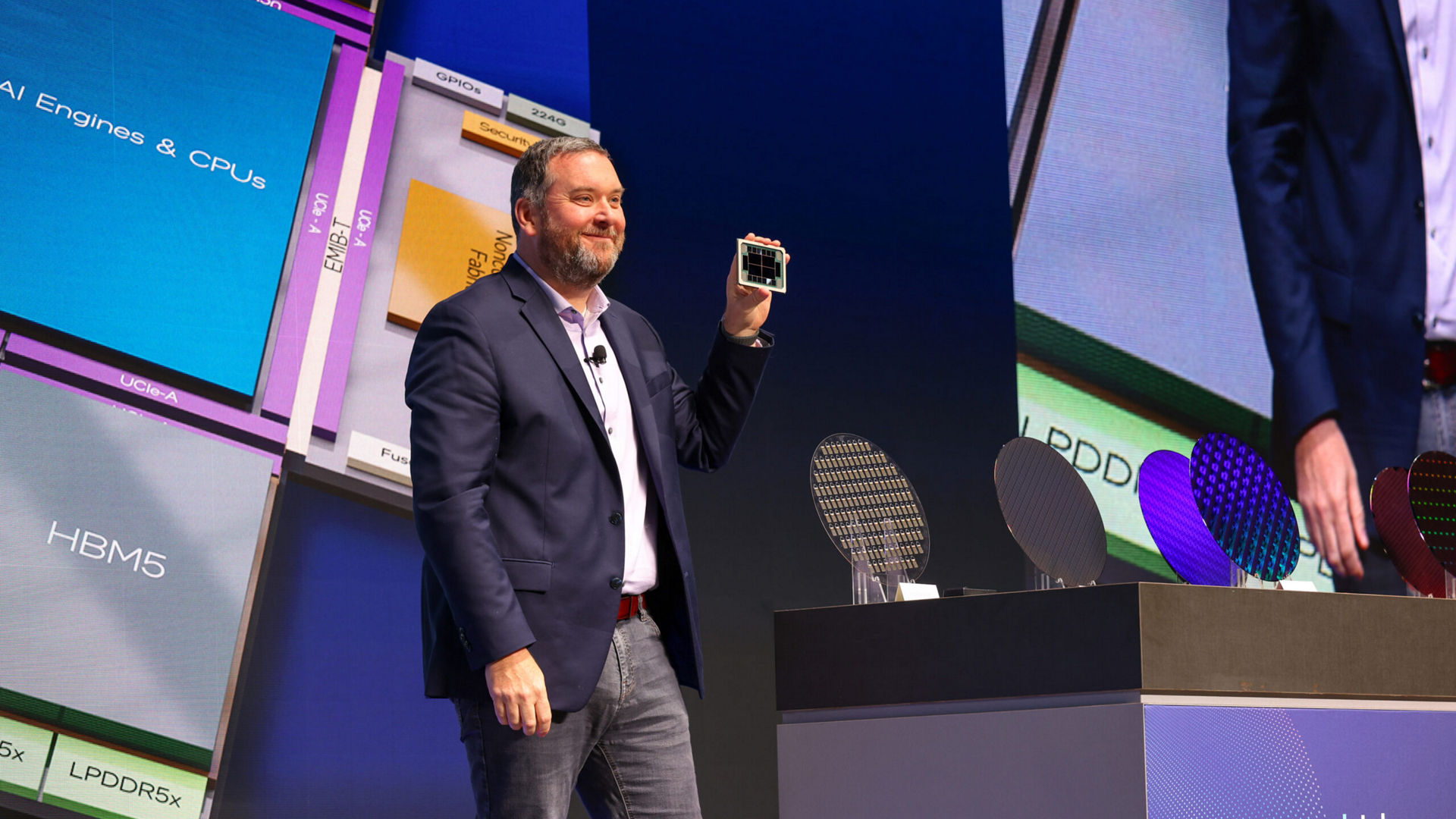 Kevin O’Buckley holds a test chip during a keynote at Intel Foundry Direct Connect.