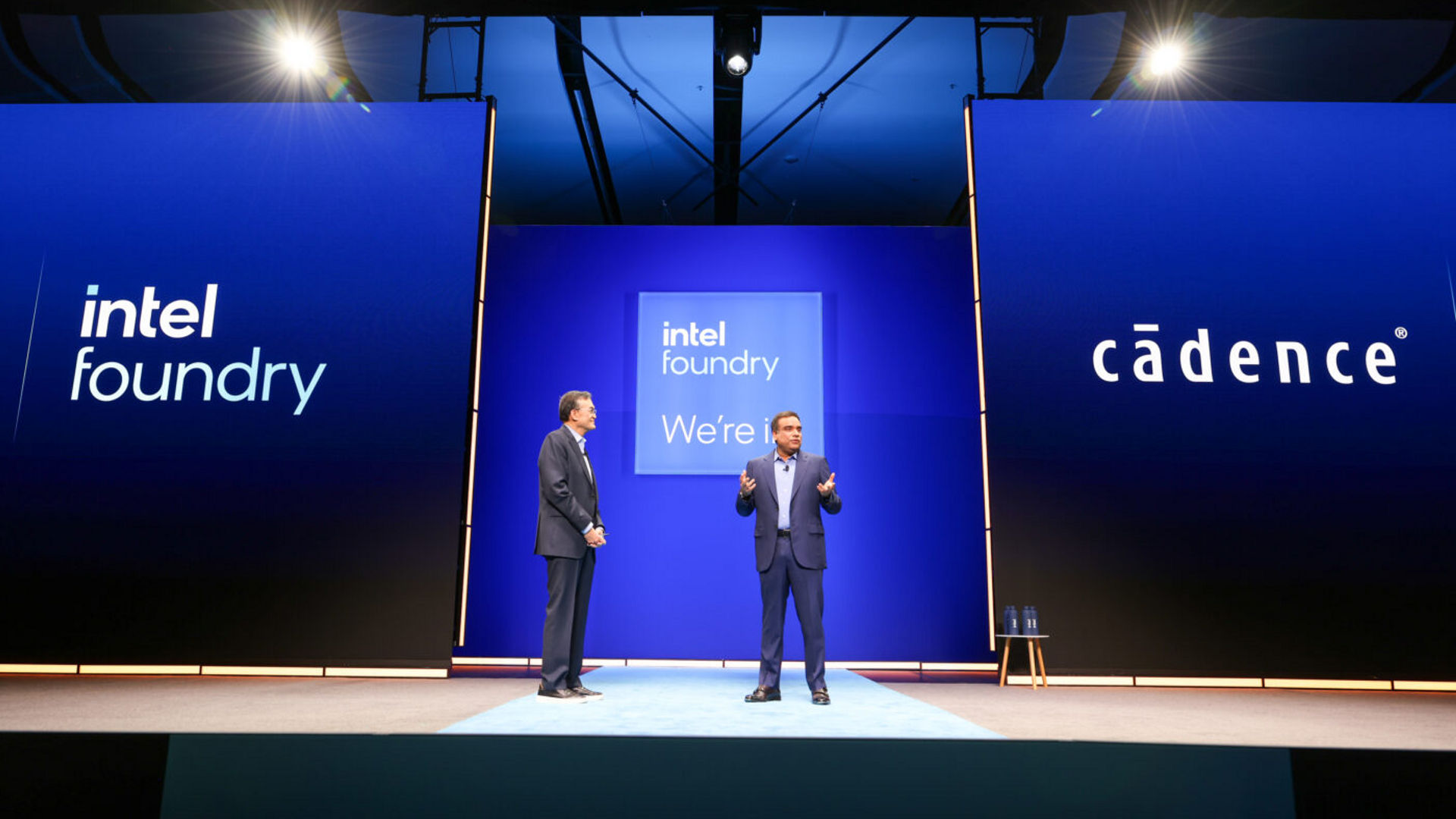 Lip-Bu Tan and Anirudh Devgan on stage between Intel Foundry and Cadence displays.