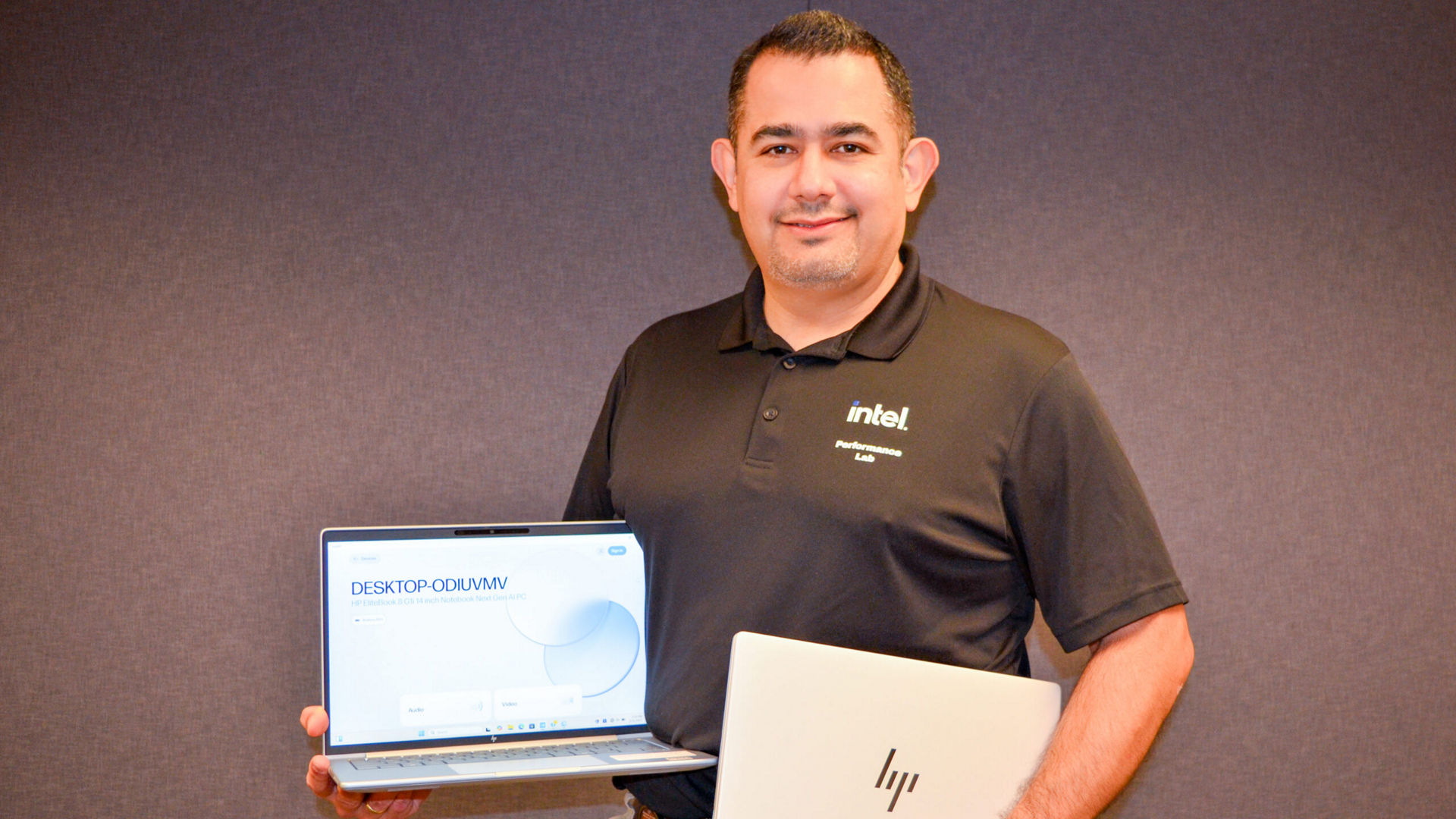 Intel engineer Ivan Chacon holding two HP Elitebook 8 AI PC laptops.