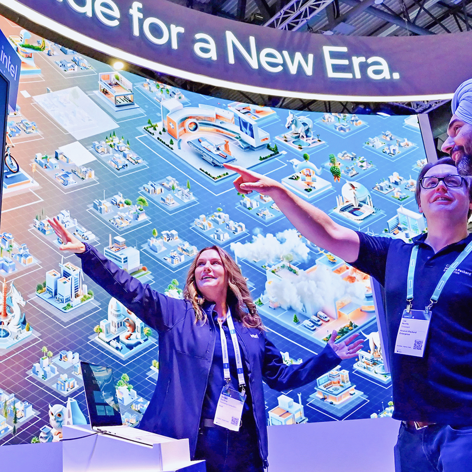 Three people are engaged with a large, colorful digital display about AI technology. Two point at the screen while another stands nearby. The backdrop shows futuristic city elements, and a sign reads, AI on Device for a New Era.