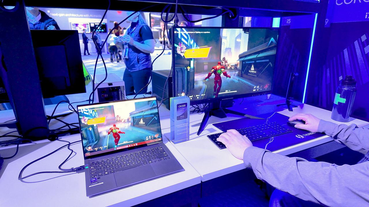Uma pessoa joga num computador de secretária e num portátil, ambos com a mesma cena de jogo.