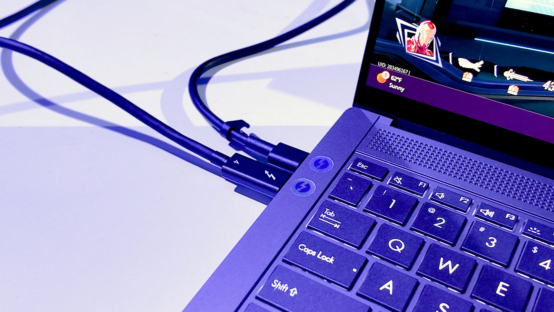 Close-up do teclado de um portátil com cabos USB-C e HDMI ligados.