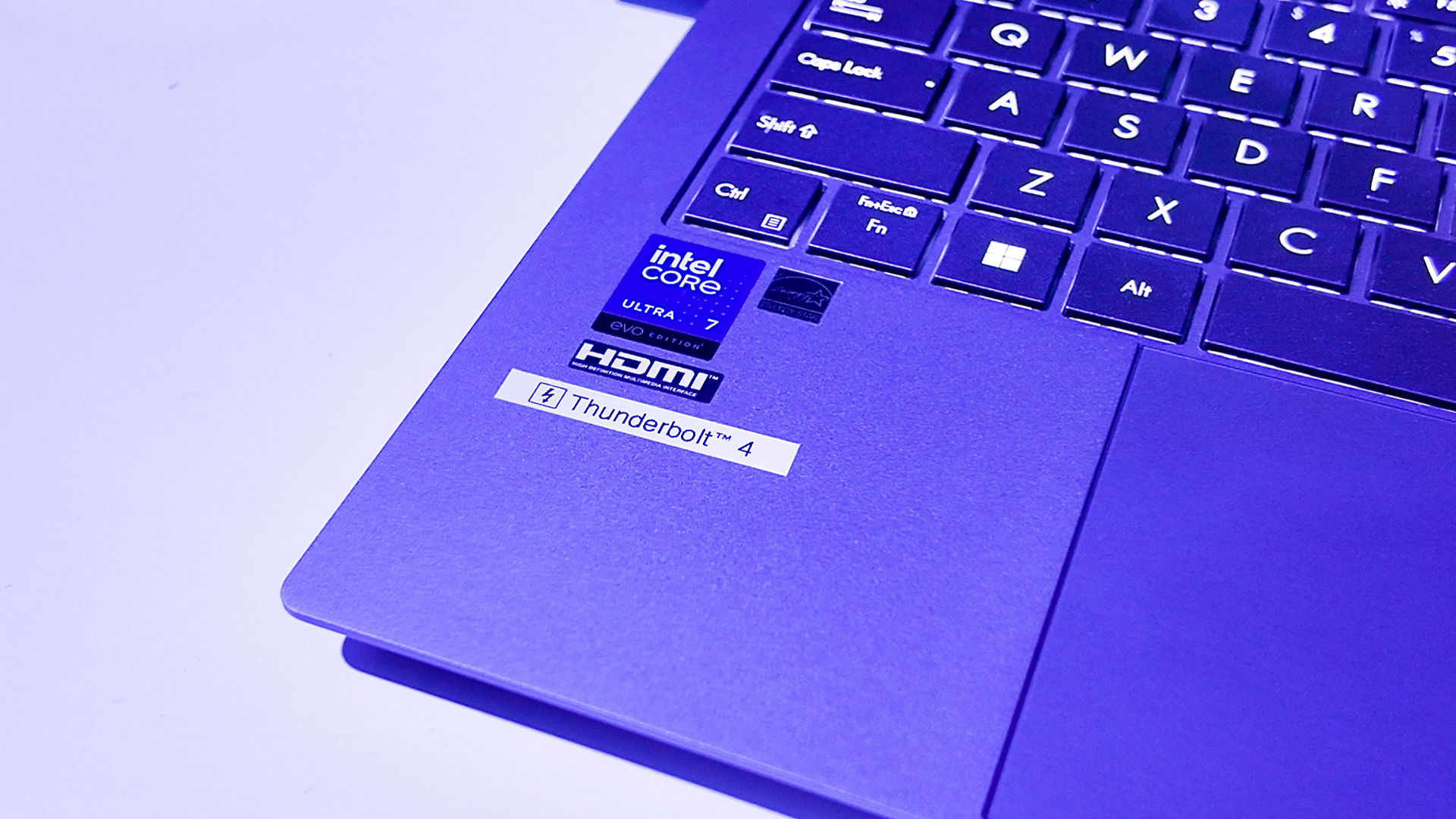 Close-up de um teclado de portátil roxo com autocolantes Intel Core i7, AMD Radeon, HDMI e Thunderbolt 4.