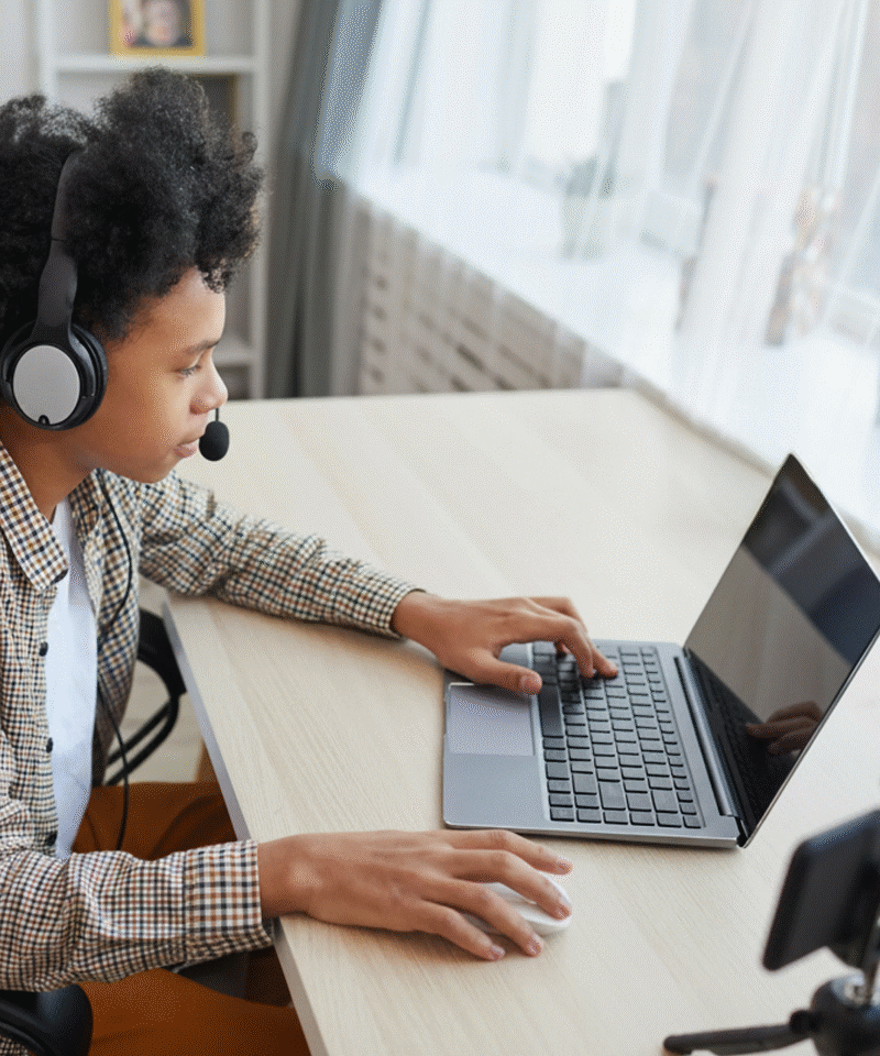 Kid using a headset and laptop at a desk