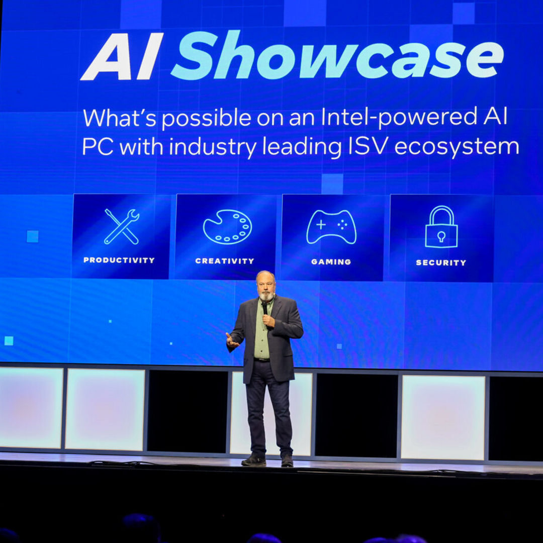 A speaker stands on stage in front of a large screen displaying AI Showcase with icons labeled Productivity, Creativity, Gaming, and Security. A QR code and an Intel logo are also visible on the screen.
