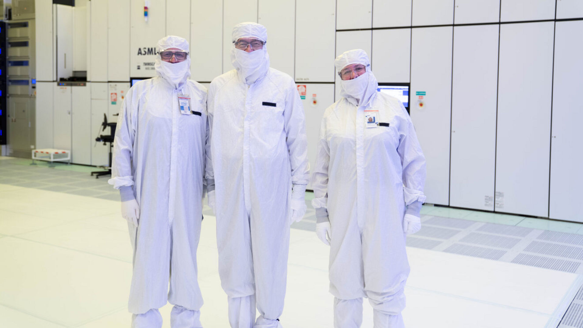 Lip-Bu Tan, Jason Reid, and Zivit Katz-Tsameret stand in cleanroom suits before an EUV lithography scanner.