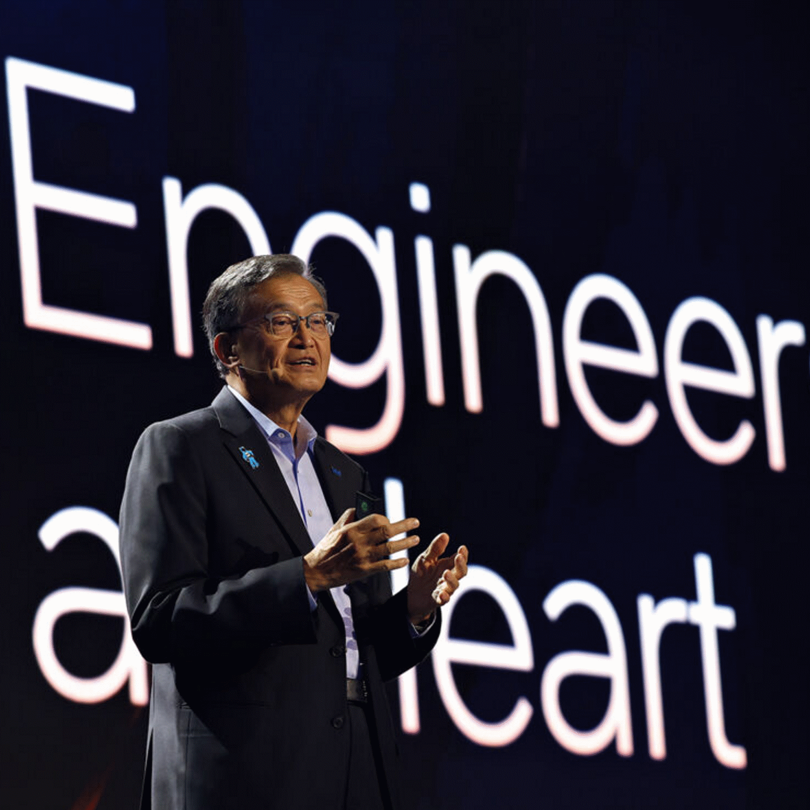 一名演讲者站在写有“Engineers at heart”的黑色舞台屏幕前。