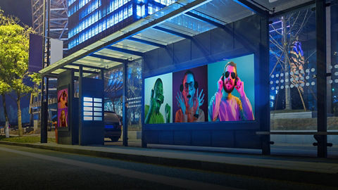 Digital billboard beside a bus stop (darkened)